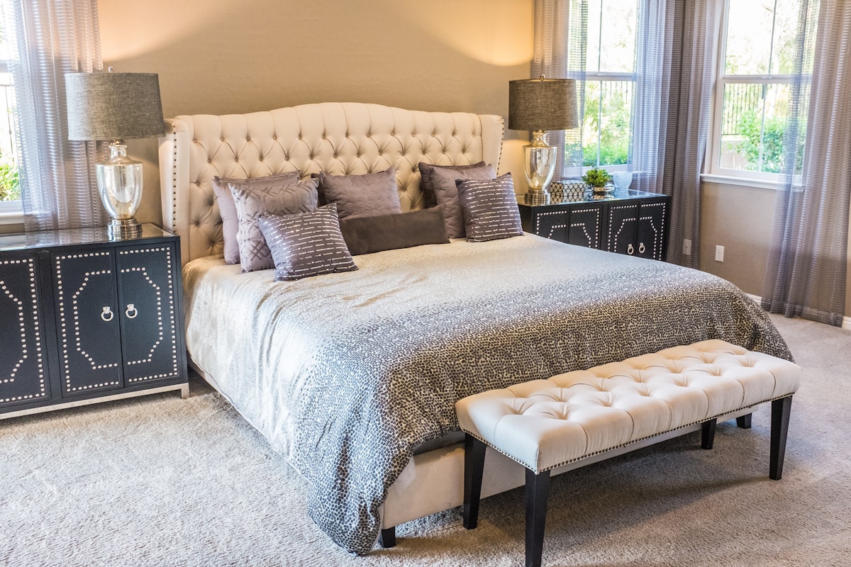 A neatly made bed with a white duvet and plump pillows in a bright bedroom