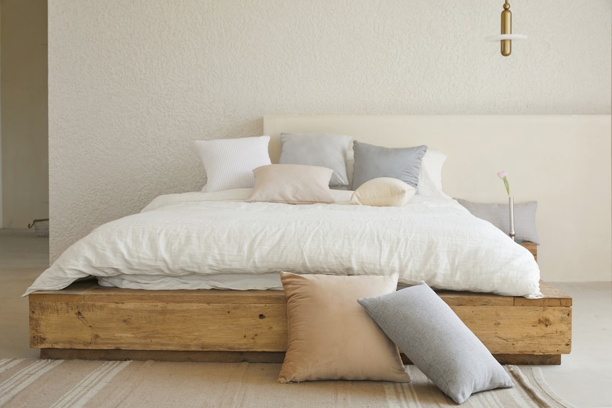 A bed with a white duvet and layered pillows in a bright bedroom - duvet layering guide UK